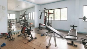 A gym with various exercise equipment, large windows, and a mirror.
