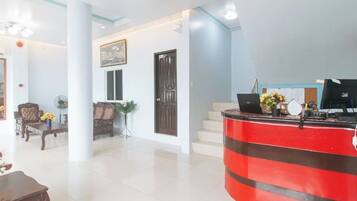 A hotel lobby with a reception desk, seating area, and a staircase.