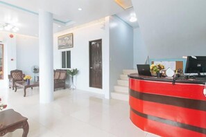 A hotel lobby with a reception desk, seating area, and a staircase.