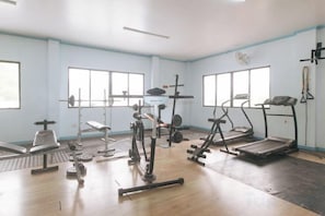 A gym with various exercise equipment, large windows, and a wooden floor. - RedDoorz @ Raj Inn Guimaras (Jordan)