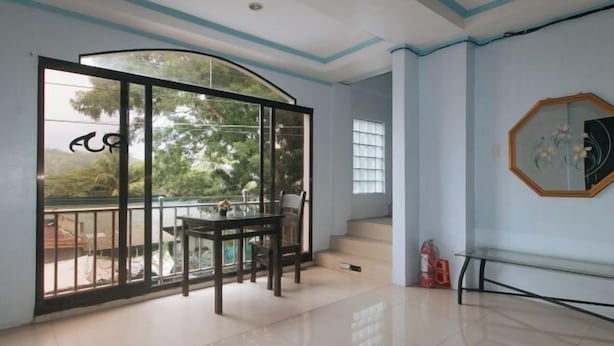 A spacious room with a large sliding glass door leading to a balcony, a dining table, and a staircase.