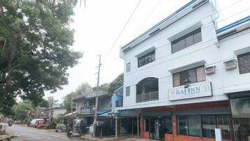 A multi-story building with a sign for 'RAJINN' hotel. There are storefronts on the ground floor, and the building has a flat roof.