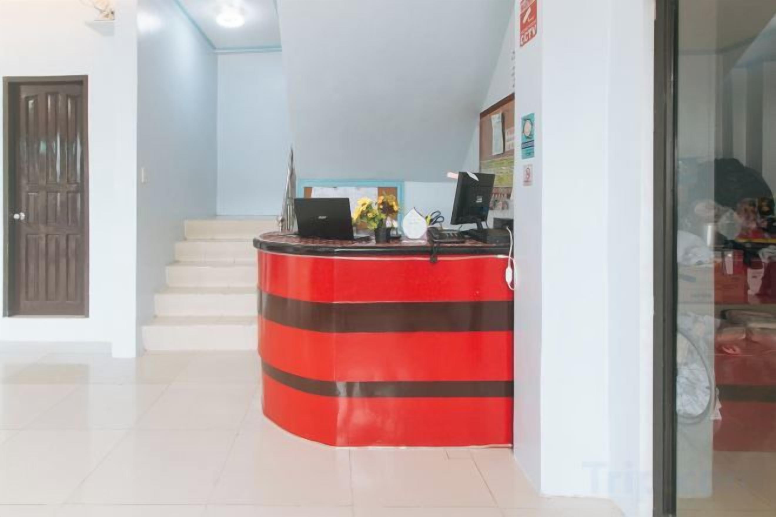 A reception desk with a computer, a telephone, and a small table with a vase of flowers.