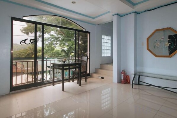 A room with a sliding glass door leading to a balcony, a dining table with chairs, and a staircase.