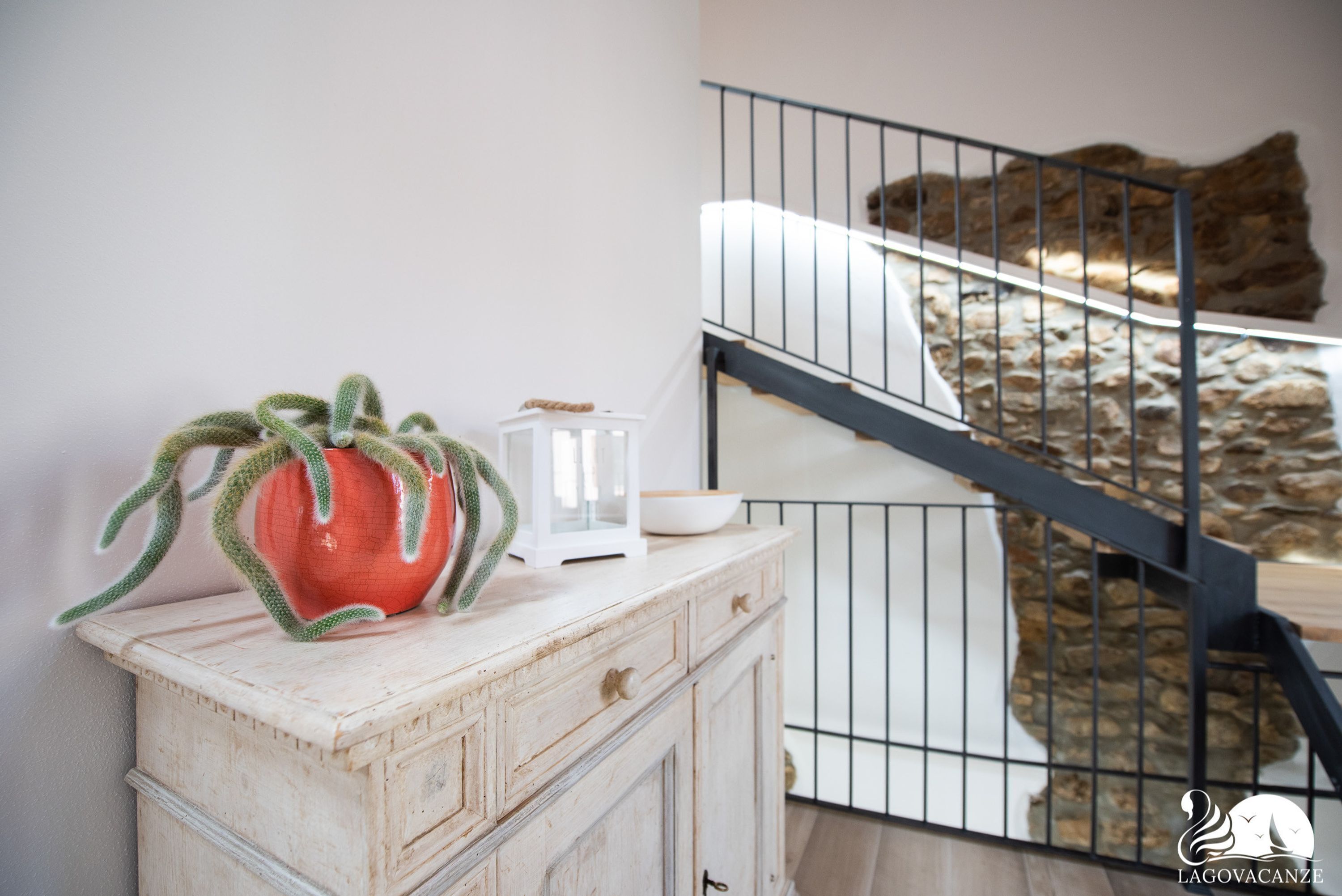 A rustic kitchen with a white cabinet, a red tomato, and a white lantern.