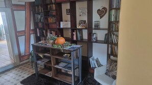 A cozy reading nook with a wooden table, a pumpkin, and a bookshelf filled with books. - Schmuckstück Maikammer - extraordinary apartments in the heart of Maikammer Whg. 1 (Maikammer)