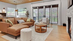 A modern living room with a sectional sofa, a round coffee table, and a fireplace. - Modern home with 2 master bedrooms, private hot tub, garage and mountain views (Silver Star Mountain)