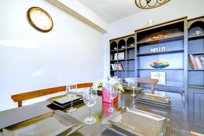 A dining area with a wooden table set for four, glasses, and a vase of flowers. - Spacious Top Floor at Stampede w/ Free Parking, AC (Calgary)