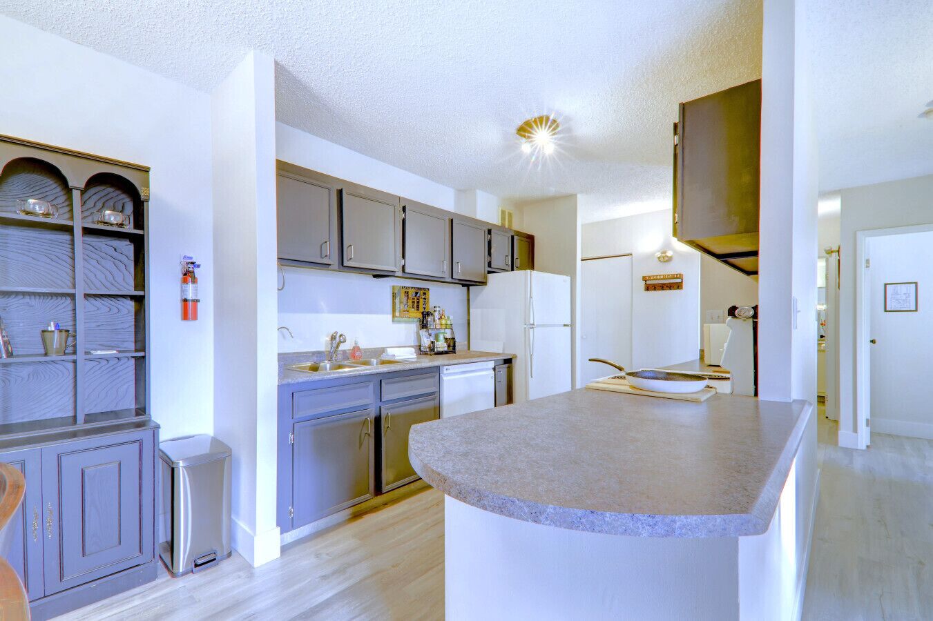 A modern kitchen with grey cabinets, a central island, and a built-in oven.