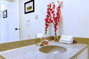 A bathroom with a granite sink, a mirror, a towel rack, and a framed picture on the wall. - Spacious Top Floor at Stampede w/ Free Parking, AC (Calgary)