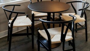 Un comedor con una mesa redonda y cuatro sillas, una lámpara de pie y un cuadro en la pared.