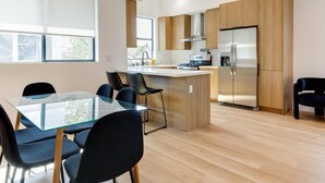 A modern kitchen with a central island, stainless steel appliances, and wooden cabinetry. - Modern Luxe Retreat Three-Bedroom #4 (Los Angeles)