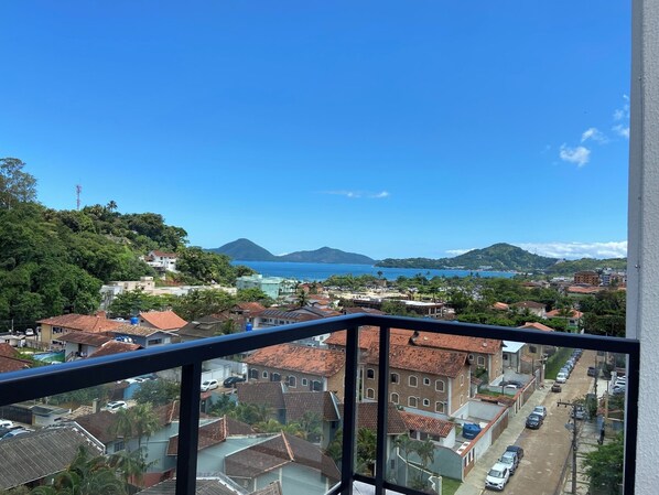 Eine Küstenstadt mit Gebäuden, blauem Himmel und Blick auf Meer und Berge.
