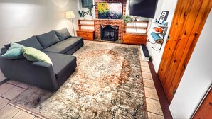 Una sala de estar con un sofá, una chimenea, un televisor y una puerta de madera.