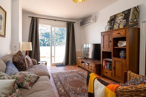 A living room with a sofa, TV, wooden cabinet, and a patterned rug.