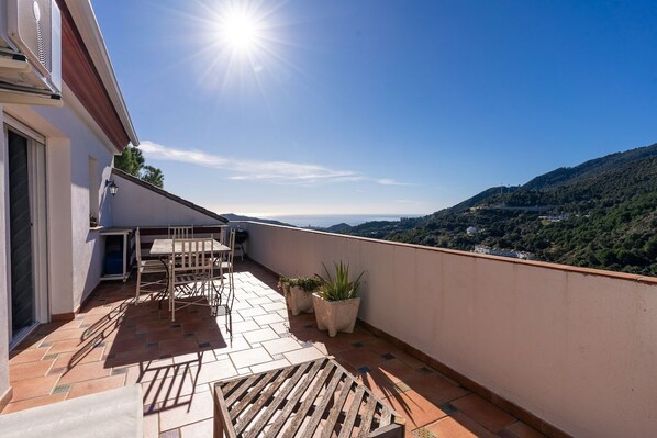 A rooftop terrace with a table and chairs, potted plants, and a view of a hilly landscape. - El Cerezal - Mountain Retreat (Ojen)