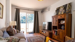 Una sala de estar con sofá, televisor, mueble de madera y alfombra estampada.