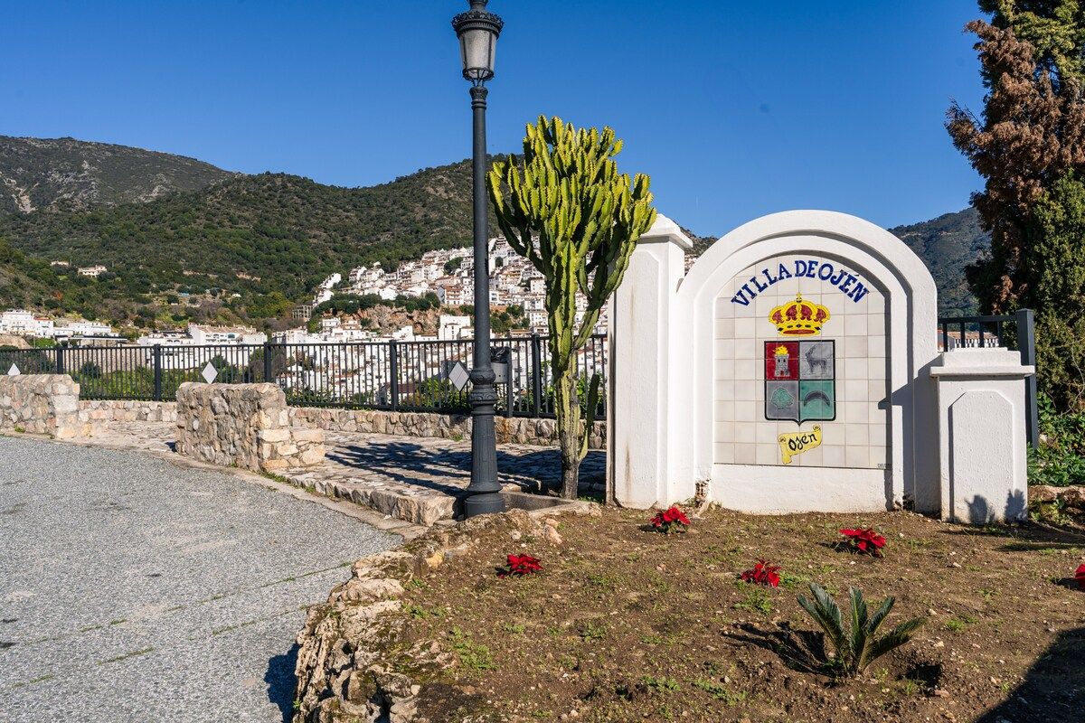 Una villa llamada 'Villa De Ojen' con vistas despejadas del paisaje circundante y una montaña al fondo.