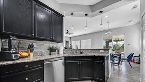 A modern kitchen with dark cabinets, stainless steel appliances, and a granite countertop. - Charming 4-bedroom house with private pool and spa in brilliant Indio (Indio)