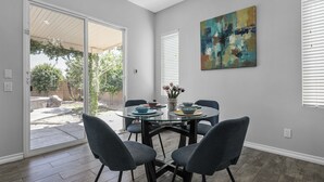 A dining area with a glass table, four chairs, and a vase with flowers. - Charming 4-bedroom house with private pool and spa in brilliant Indio (Indio)