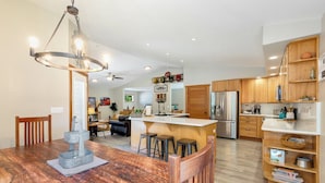 Een moderne keuken met houten kastjes, een centraal eiland en een eetgedeelte met een houten tafel en stoelen.