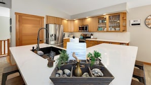 Een moderne keuken met houten kastjes, roestvrijstalen apparatuur en een marmeren eiland met decoratief middelpunt.