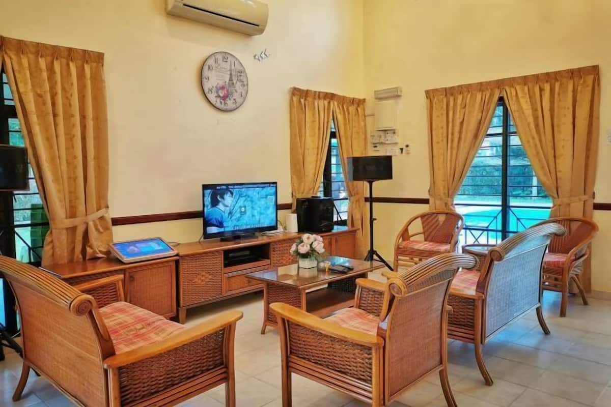 A room with wicker furniture, a television, and a clock on the wall.