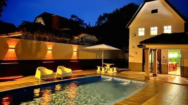 A swimming pool with lounge chairs and a patio area, surrounded by a house and trees. - Yussy Homestay at Afamosa Villa (Alor Gajah)