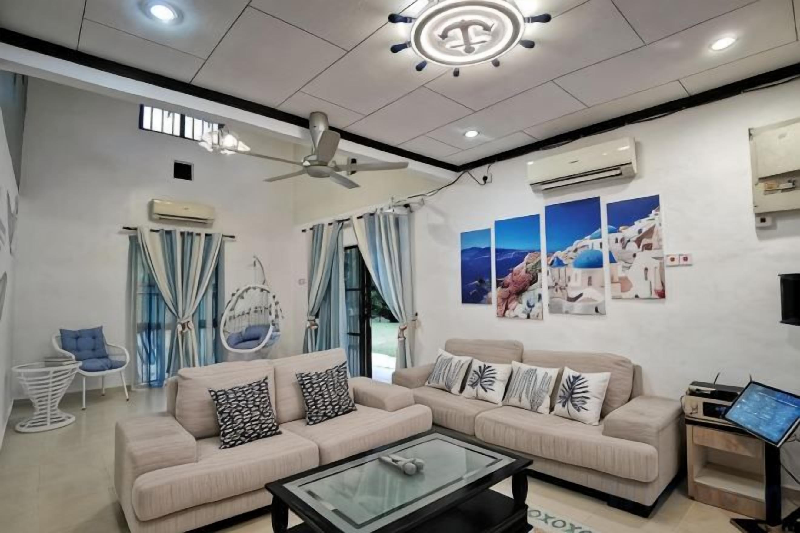 A modern living room with a sofa set, a coffee table, a ceiling fan, and wall-mounted air conditioning units.