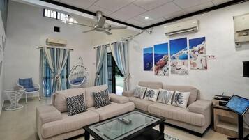 A modern living room with a sofa set, a coffee table, a ceiling fan, and wall-mounted air conditioning units.