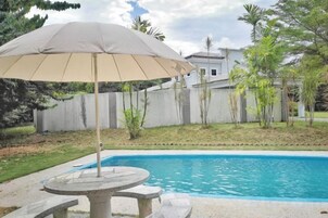 A swimming pool with a stone table and an umbrella.