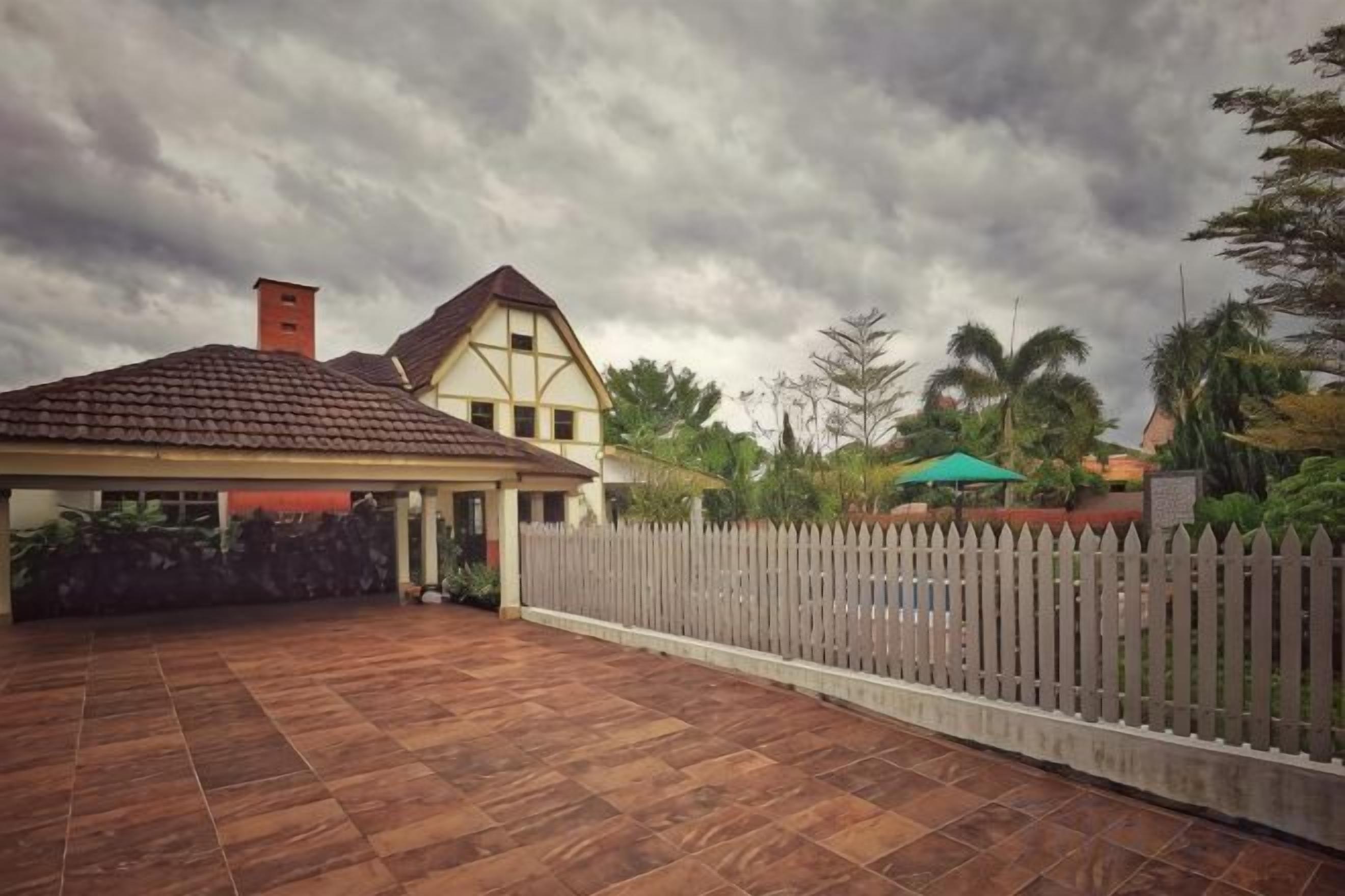 A residential property with a paved patio, a detached garage, and a white picket fence.