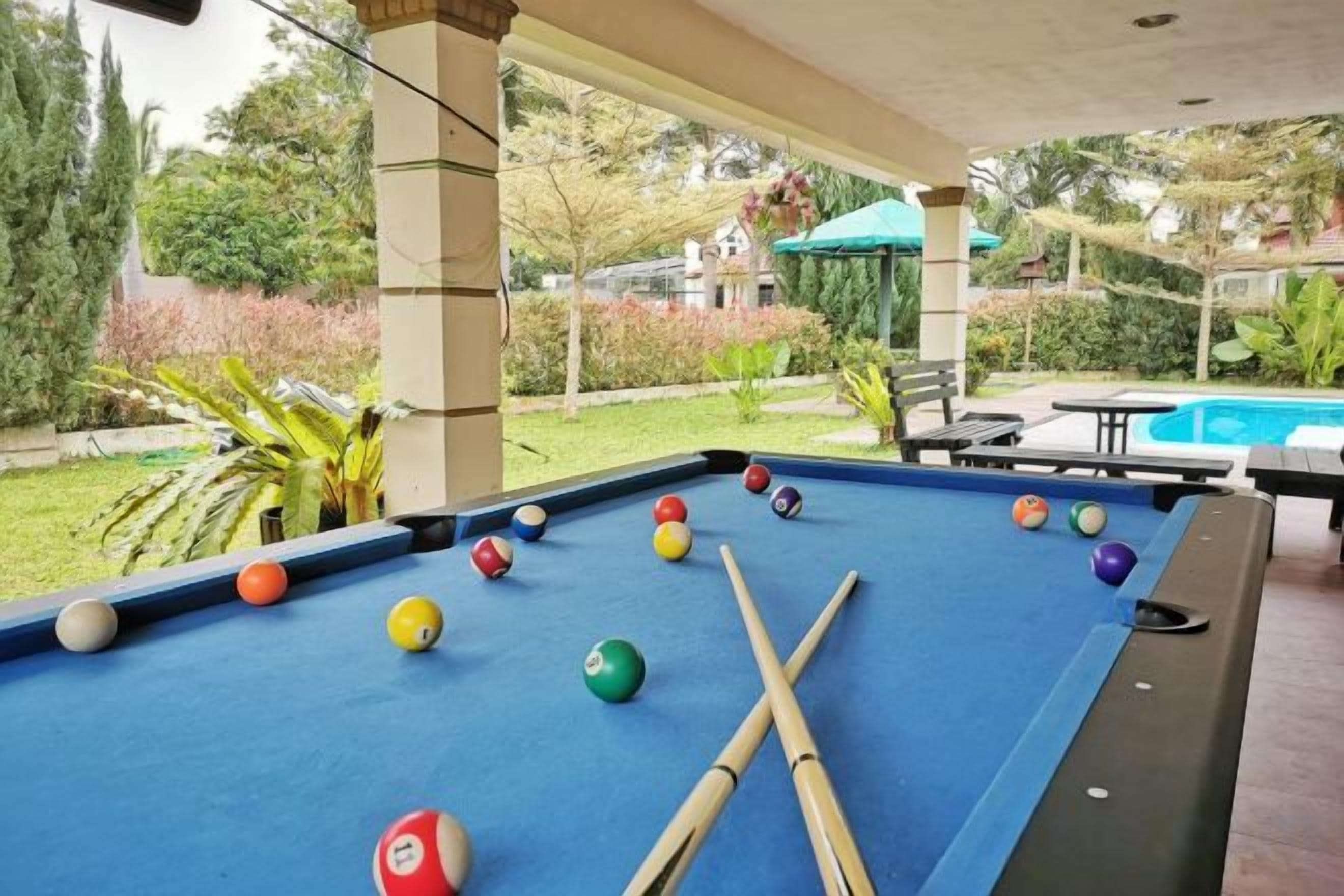 A pool table with billiard balls and cues, a pool table, and a pool table in a covered outdoor area.