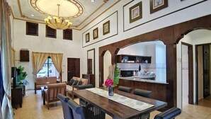A spacious living area with a dining table, sofas, and a kitchen in the background. - Yussy Homestay at Afamosa Villa (Alor Gajah)