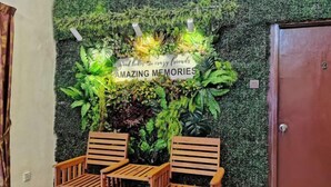 A reception area with a green wall, two wooden chairs, and a sign that reads 'good times to crazy friends AMAZING MEMORIES'. - Yussy Homestay at Afamosa Villa (Alor Gajah)