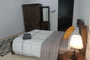 A bedroom with a bed, a wooden wardrobe, a mirror, and a bedside lamp. - Sky312 Muslim Homestay (Langkawi)
