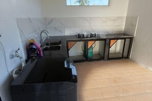 Een keuken met een zwart spoelbak, een gasfornuis en een aanrecht.