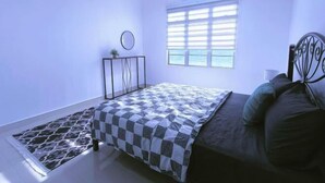 A bedroom with a bed, a window with blinds, a small table with a plant, and a radiator. - Sky312 Muslim Homestay (Langkawi)