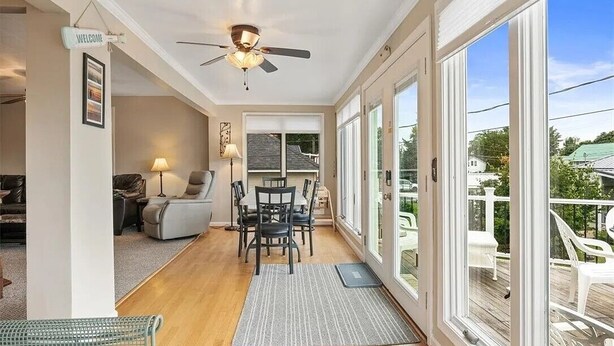 A spacious living area with a dining table, chairs, a sofa, and a ceiling fan. - Sodus Bay View at the Point (Sodus Point)