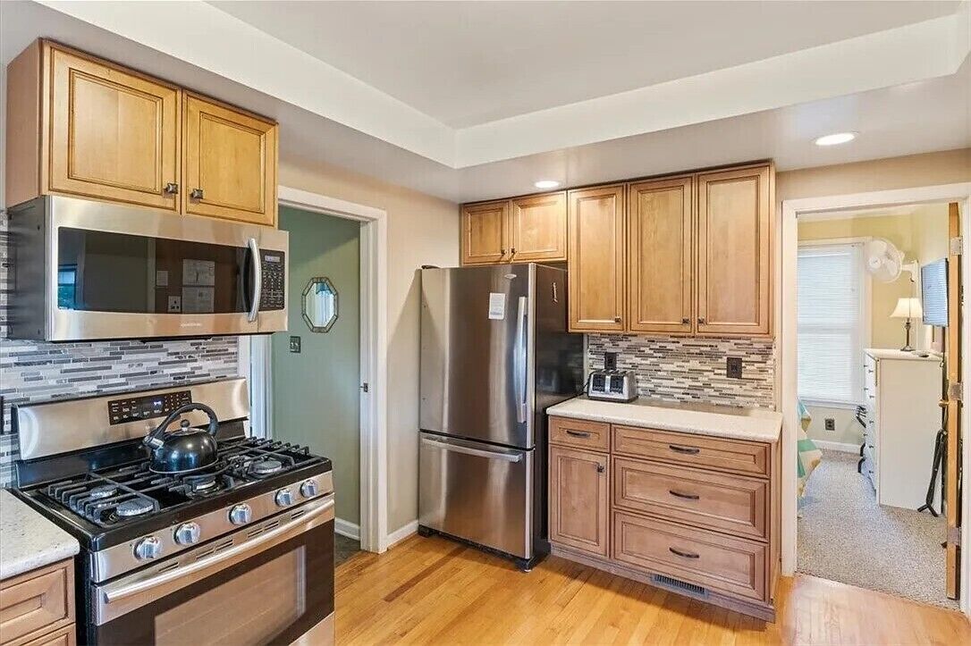 A modern kitchen with wooden cabinets, stainless steel appliances, a microwave, a refrigerator, and a toaster.