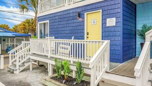 A two-story building with a blue exterior, white railings, and a yellow door marked with the number 11. - Boardwalk Inn (Carolina Beach)