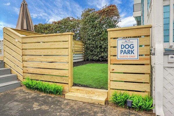 A wooden dog park gate with a sign indicating it is for guests only. - Boardwalk Inn (Carolina Beach)