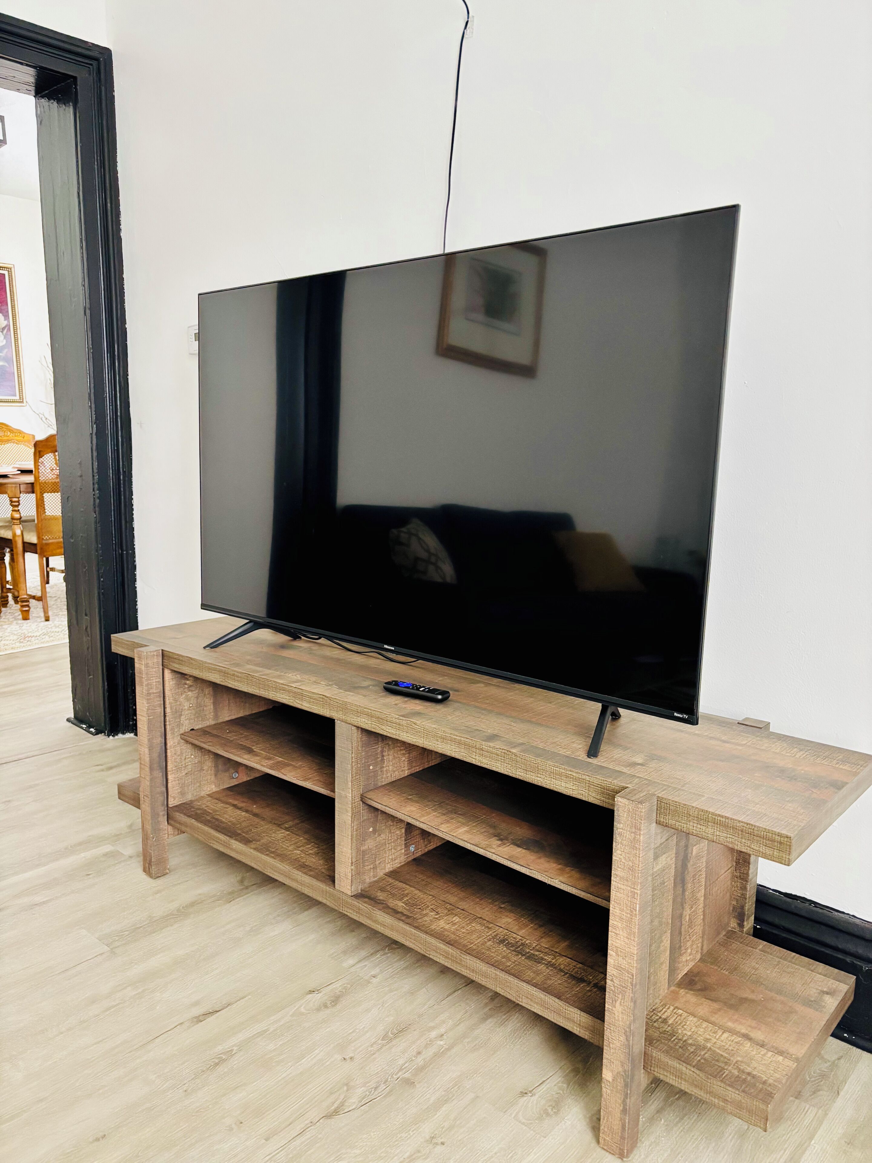 A wooden TV stand with a flat-screen TV and a remote control on it.