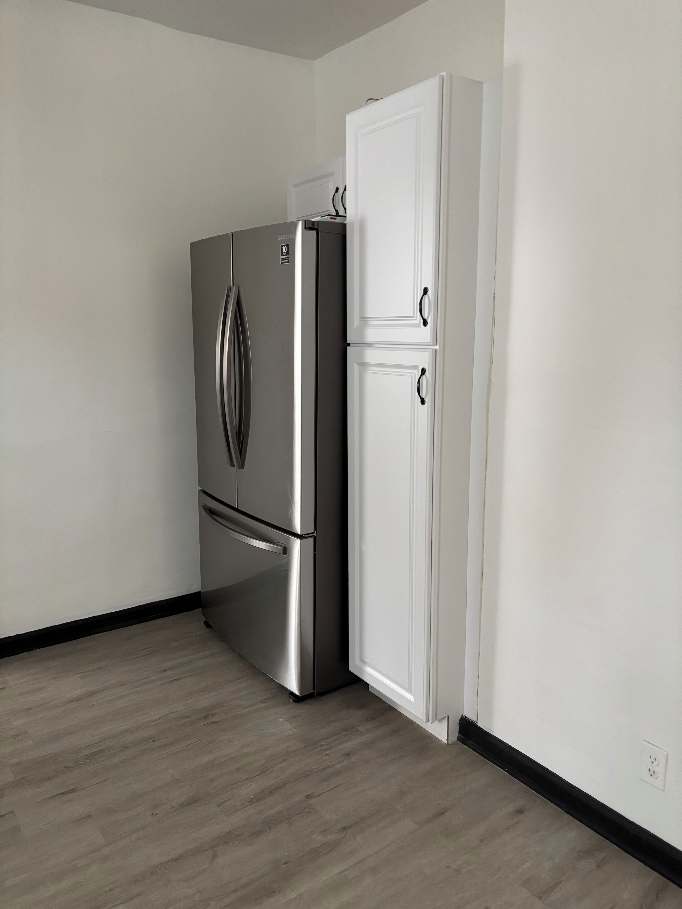Una cocina con un refrigerador de acero inoxidable y un armario blanco de dos puertas.