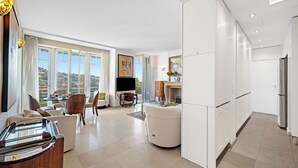Una sala de estar moderna con un ventanal grande, un televisor de pantalla plana y un comedor con mesa y sillas.