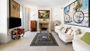 Una sala de estar con una televisión de pantalla plana, una chimenea, un sofá y un cuadro de una bicicleta.