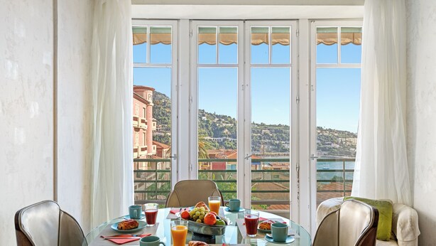 Un área de comedor con una mesa de vidrio, sillas y vistas a un paisaje costero.