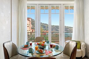 Un espace repas avec une table en verre, des chaises et une vue sur un paysage côtier.