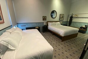 Une chambre d’hôtel avec deux lits, un miroir rond, une table de chevet et un sol à motifs.