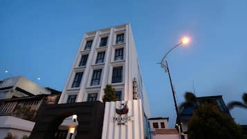 A hotel building with a modern facade, a prominent entrance, and a street lamp.
